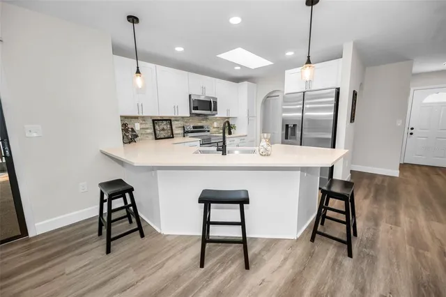a large kitchen with a table chairs refrigerator and wooden floor