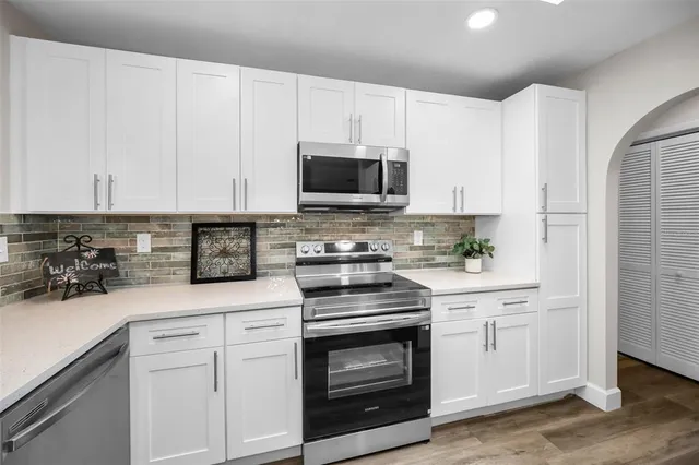 a kitchen with white cabinets and stainless steel appliances