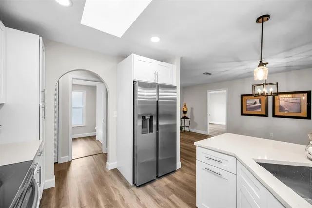 a kitchen with stainless steel appliances granite countertop a refrigerator a sink and wooden floor