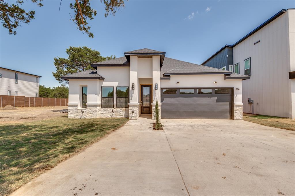 3913 Blue Ridge Boulevard Dallas, TX 75233 - Photo 1 of 25 Contemporary exterior with a white stucco finish, stone veneer accents, and a dark shingle roof