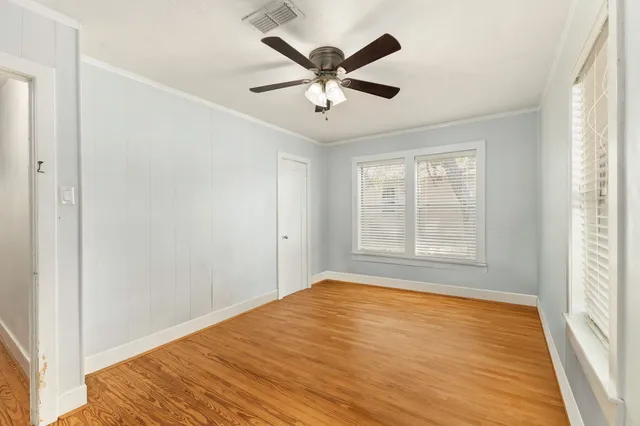 a view of empty room with wooden floor and fan