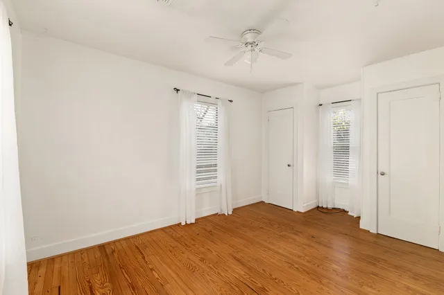 a view of empty room with wooden floor and fan