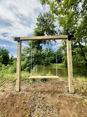 a view of a small yard in front of a house with a large tree and plants