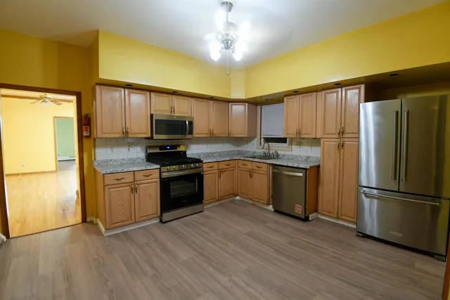 a kitchen with granite countertop stainless steel appliances a refrigerator stove top oven and cabinets