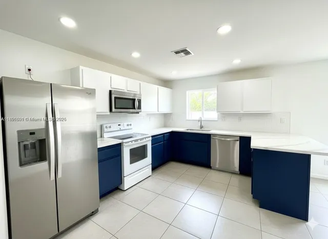 a large kitchen with stainless steel appliances granite countertop a refrigerator and a sink
