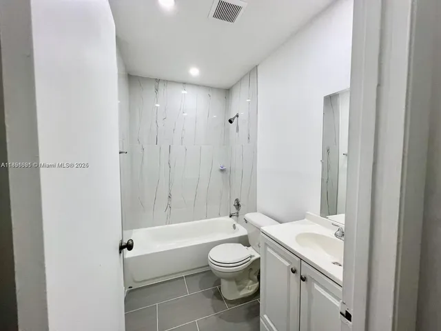 a bathroom with a granite countertop toilet a sink and a bathtub