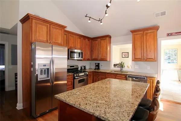 a kitchen with stainless steel appliances granite countertop a refrigerator a sink a stove and island
