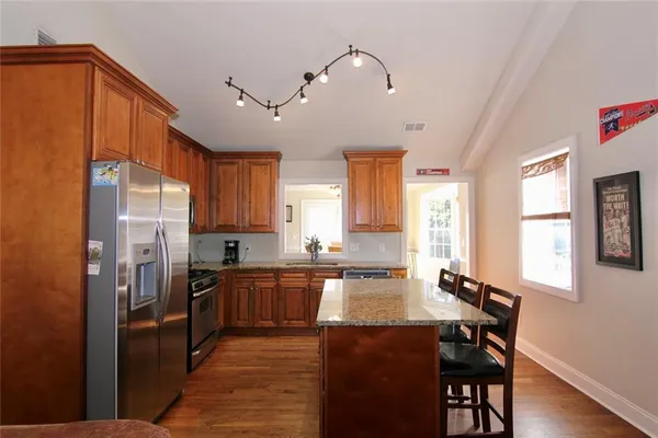 a kitchen with stainless steel appliances granite countertop sink stove refrigerator and cabinets