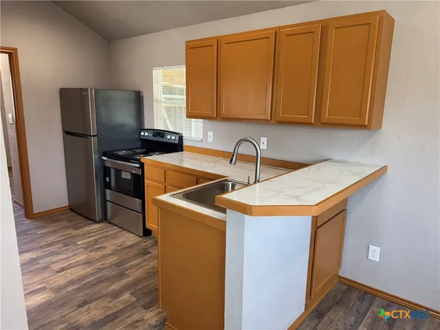 a kitchen with stainless steel appliances granite countertop a sink a stove and refrigerator