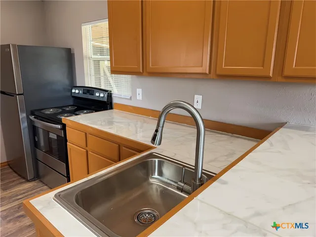 a kitchen with a sink a refrigerator and cabinets