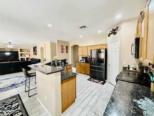 a living room with stainless steel appliances kitchen island granite countertop a sink and cabinets