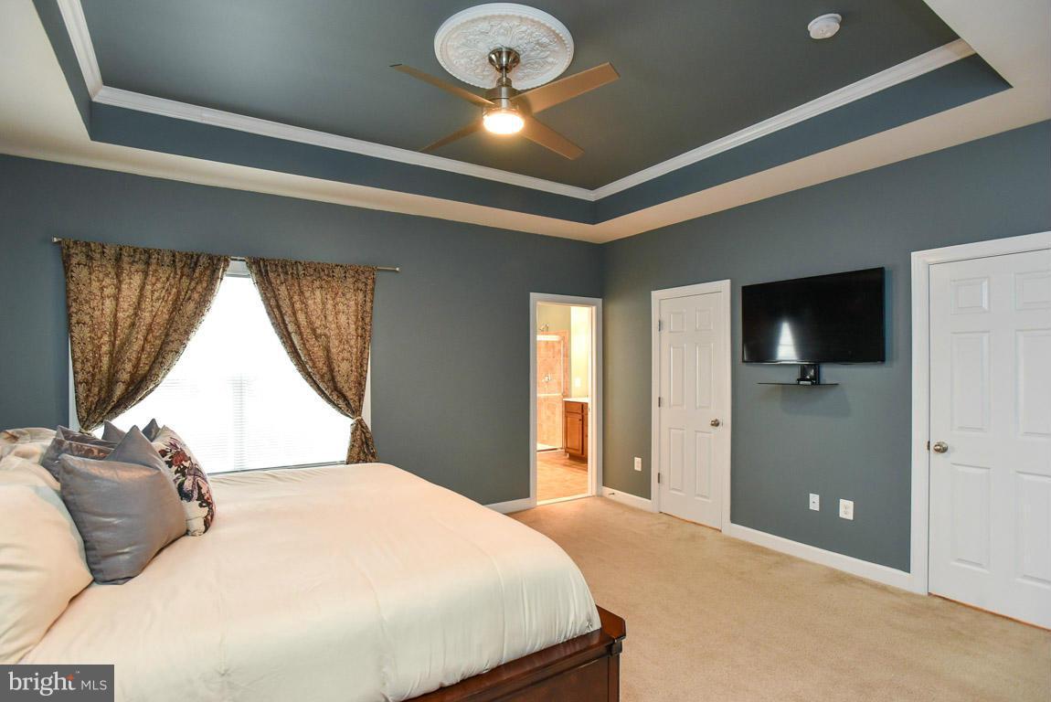 25175 Prairie Fire Square Aldie, VA 20105 - Photo 15 of 28 a bedroom with a large bed and a chandelier
