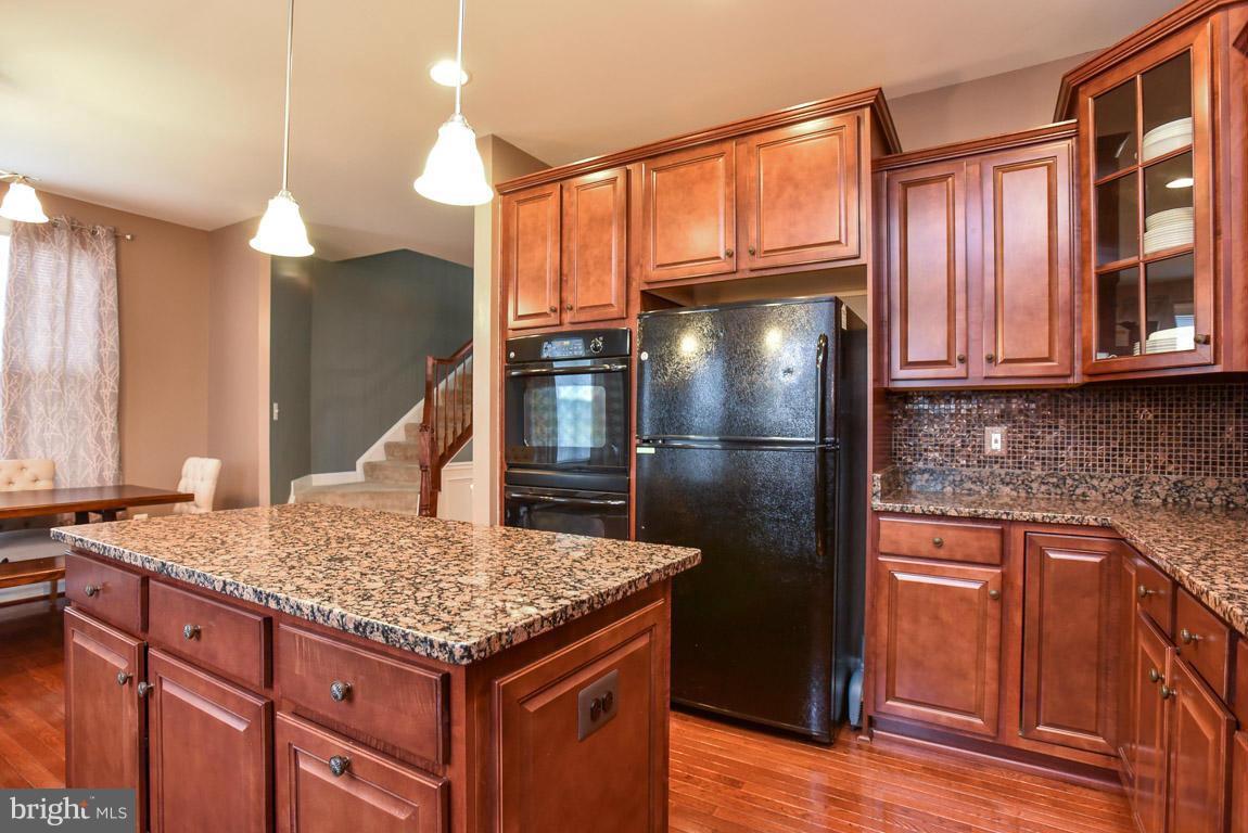 25175 Prairie Fire Square Aldie, VA 20105 - Photo 9 of 28 a kitchen with granite countertop wooden cabinets and refrigerator