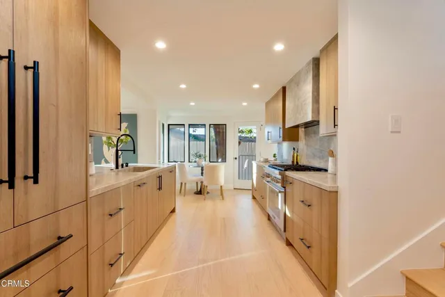 a large kitchen with stainless steel appliances a large counter top a stove and a refrigerator