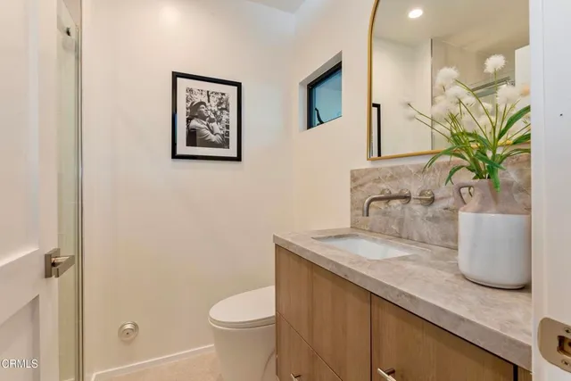 a bathroom with a granite countertop sink a toilet and mirror
