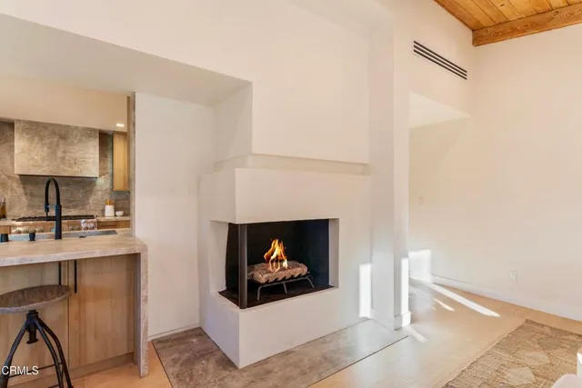 a living room with a fireplace furniture a rug and a potted plant