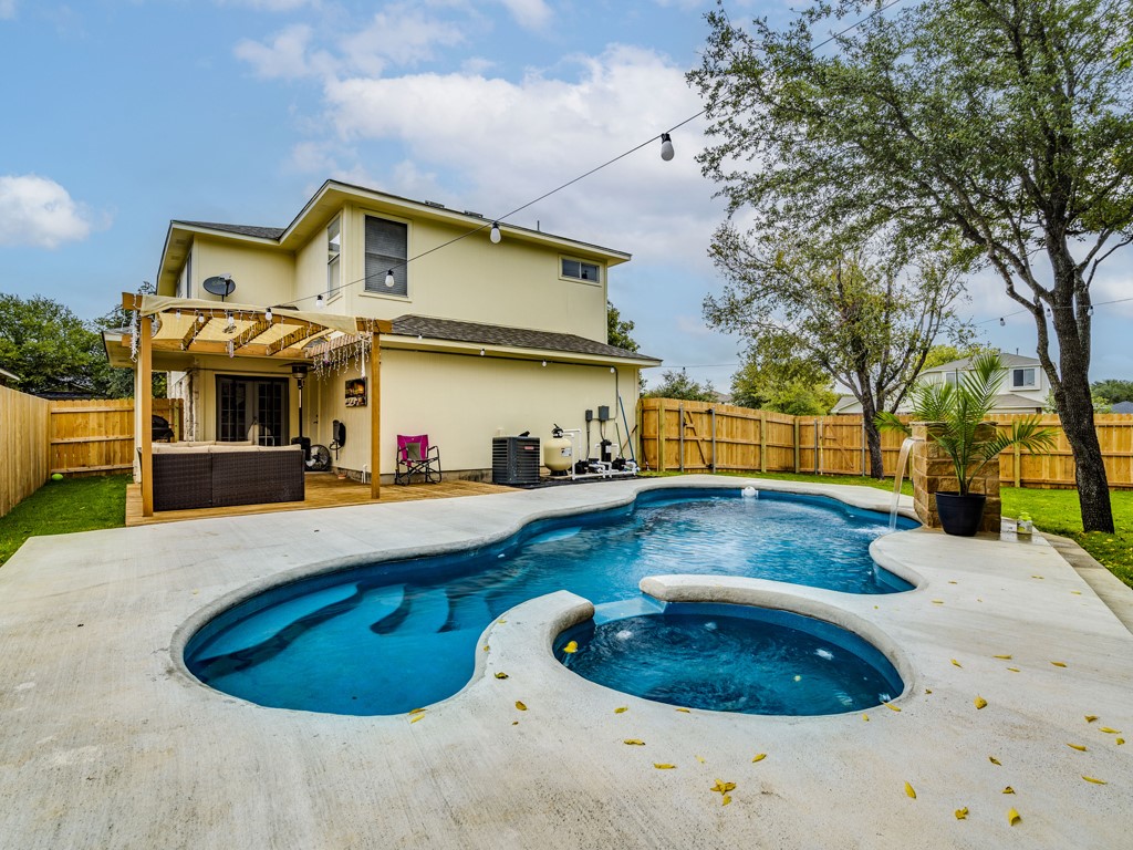 An inviting backyard oasis offers a unique in-ground pool, elevated spa, and a wooden deck for relaxation.