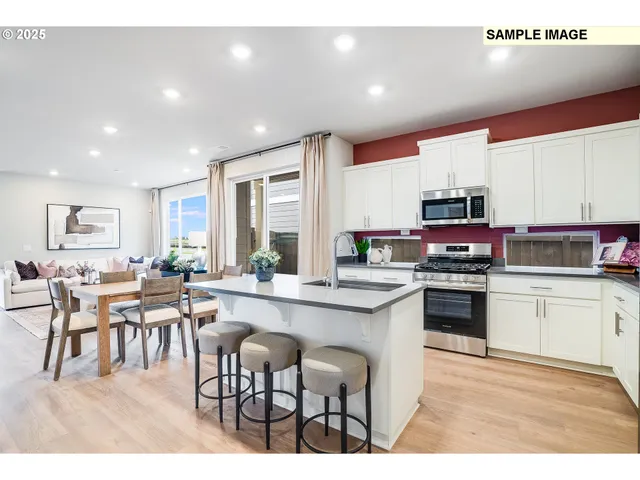 a kitchen with stainless steel appliances granite countertop a stove top oven a sink dishwasher a dining table and chairs with wooden floor