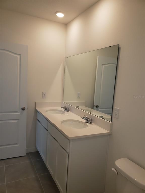 1670 Rock Elm Road Davenport, FL 33837 - Photo 16 of 28 a bathroom with a granite countertop sink a toilet and a mirror