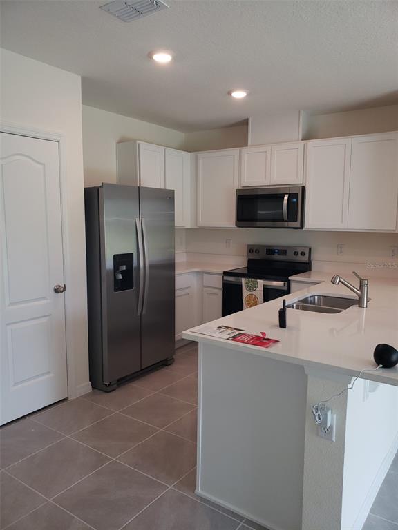 1670 Rock Elm Road Davenport, FL 33837 - Photo 9 of 28 a kitchen with stainless steel appliances a refrigerator sink and microwave