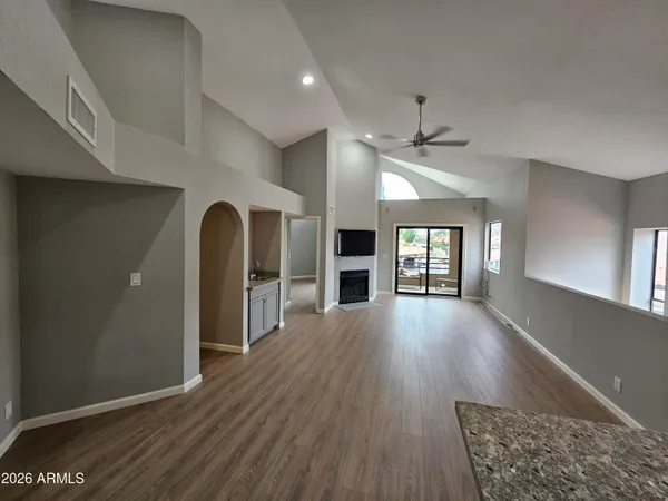a view of an empty room with window and wooden floor