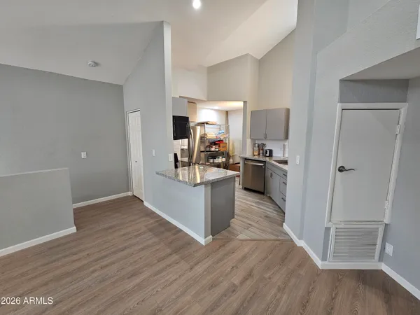 an empty room with wooden floor and a kitchen
