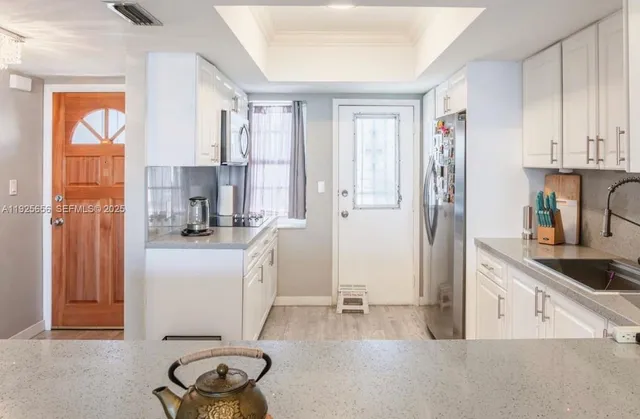 a kitchen with white cabinets and refrigerator