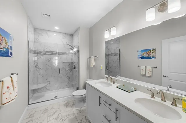 a bathroom with a granite countertop sink a toilet a mirror and shower