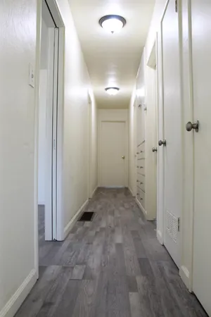 a view of an empty room with wooden floor and a window