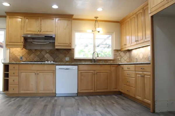 a kitchen with stainless steel appliances granite countertop a sink a stove a refrigerator and cabinets
