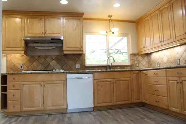 a kitchen with kitchen island granite countertop a sink cabinets and wooden floor