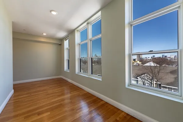 an empty room with wooden floor and window