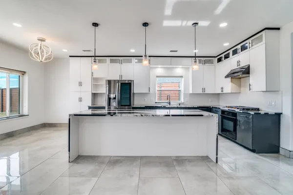 a kitchen with stainless steel appliances granite countertop a sink a stove and a refrigerator
