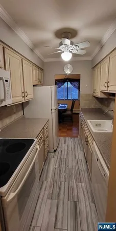 a kitchen with granite countertop a refrigerator a sink dishwasher and white cabinets with wooden floor