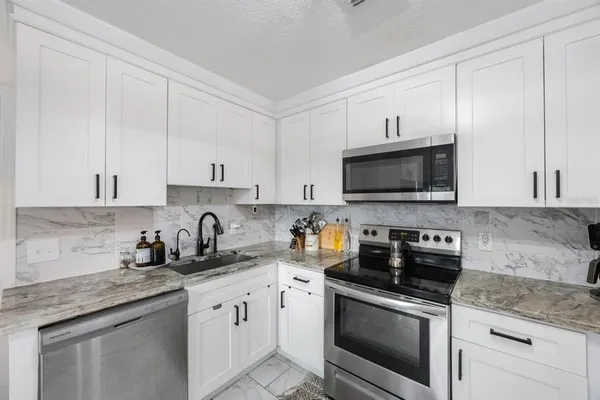a kitchen with stainless steel appliances granite countertop a sink a stove a microwave and cabinets