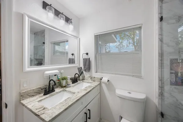 a bathroom with a granite countertop sink mirror vanity and toilet