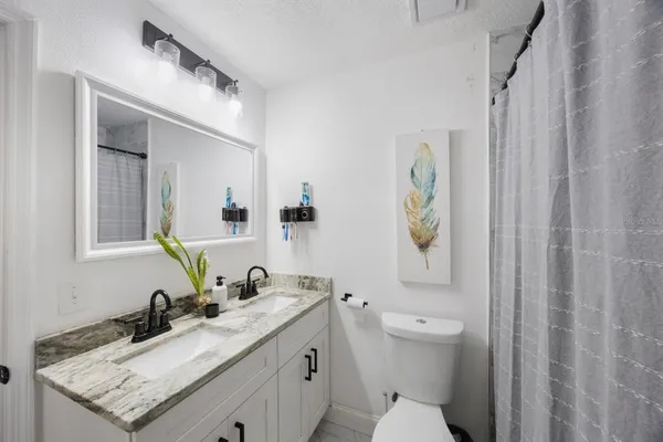 a bathroom with a granite countertop sink toilet and mirror