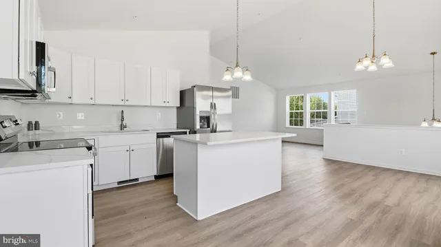 a view of a kitchen with stainless steel appliances wooden floor and a window