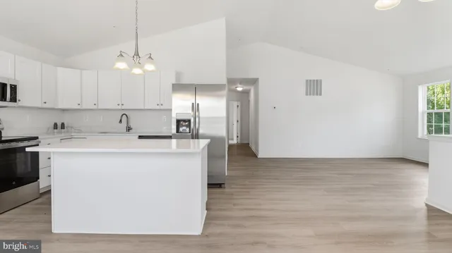 a kitchen with kitchen island white cabinets stainless steel appliances a sink and a window
