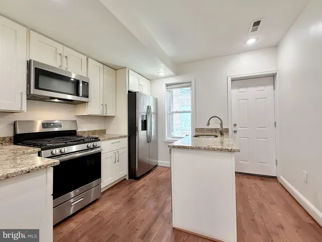 a kitchen with stainless steel appliances a sink cabinets and a wooden floor
