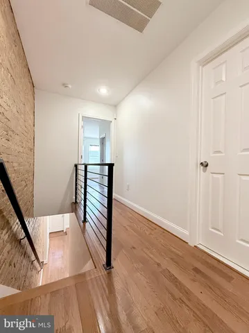 a view of a hallway with wooden floor and stairs
