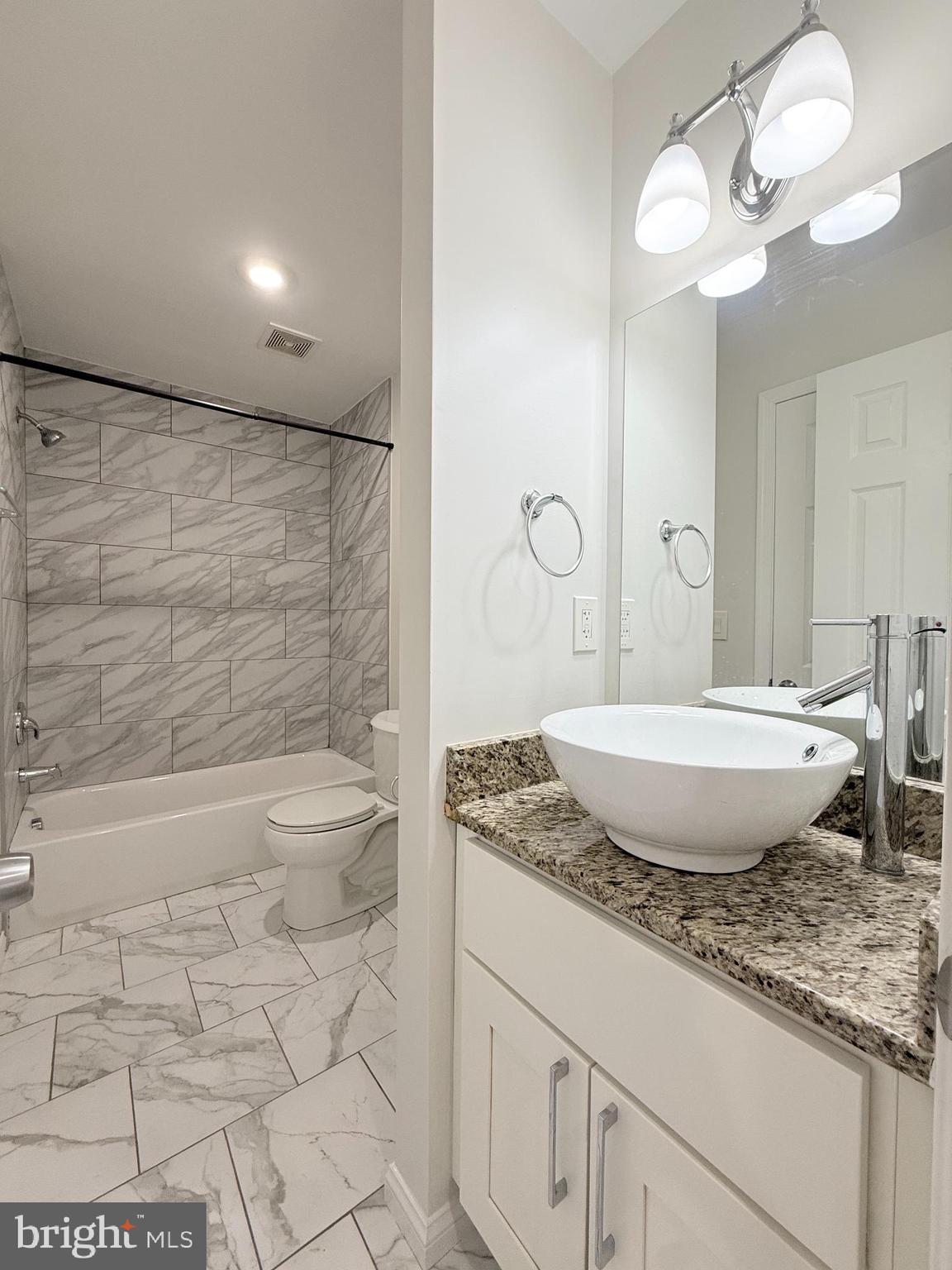 1268 Glyndon Avenue Baltimore, MD 21223 - Photo 15 of 30 a bathroom with a granite countertop sink a toilet a mirror and bathtub