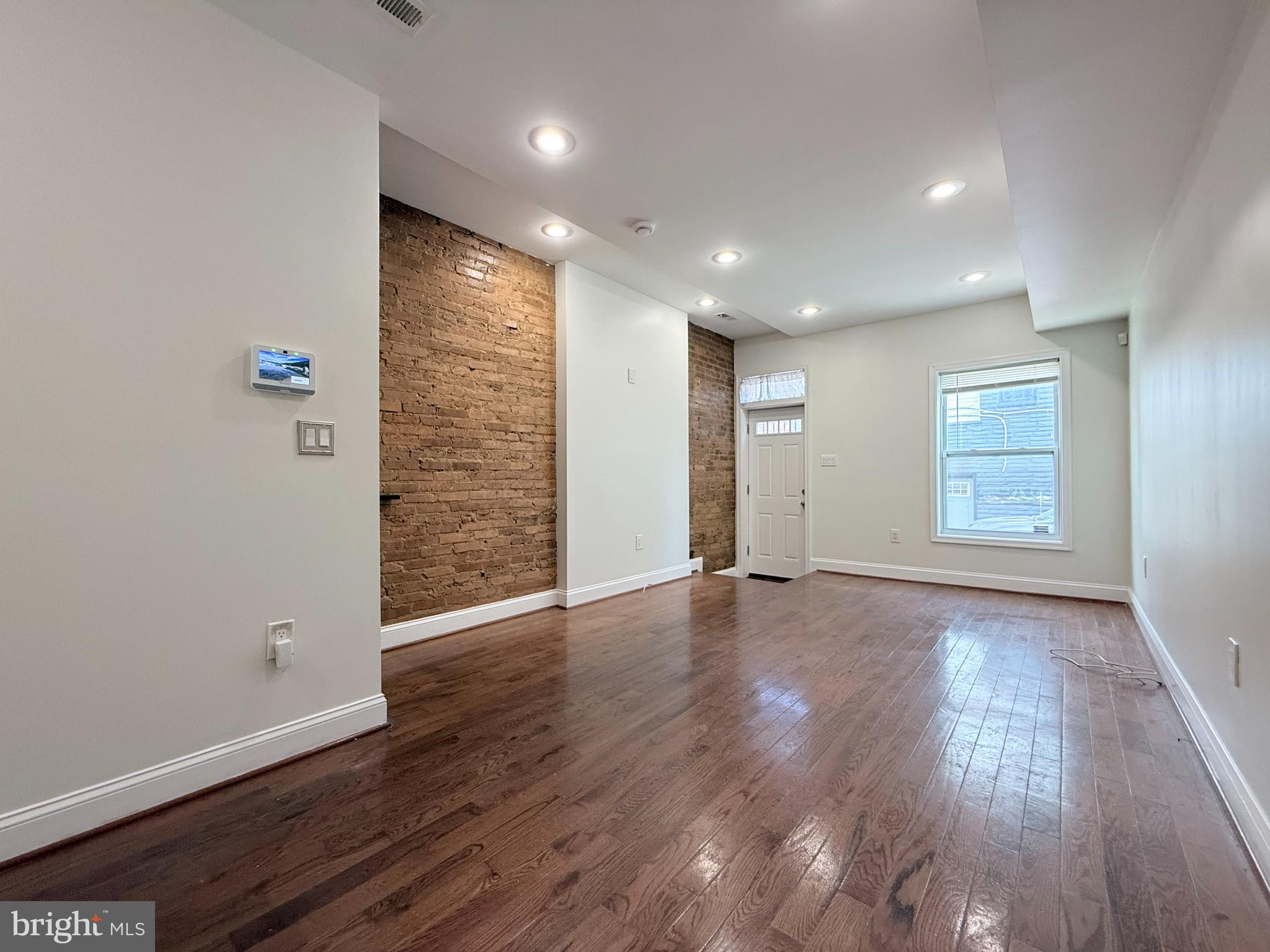 1268 Glyndon Avenue Baltimore, MD 21223 - Photo 2 of 30 a view of an empty room with wooden floor and a window