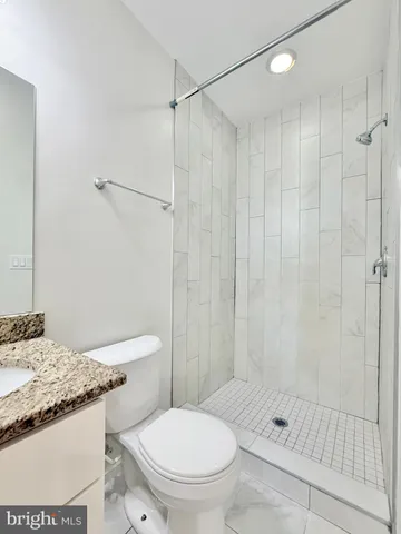 a bathroom with a granite countertop sink a toilet and shower