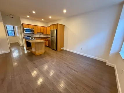 a large kitchen with stainless steel appliances a large counter top a stove and a refrigerator