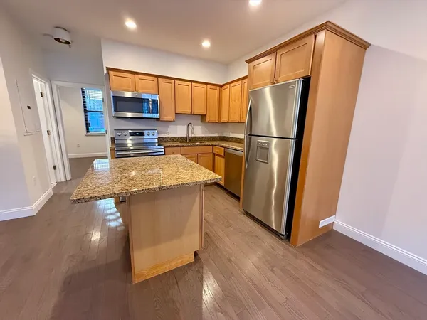 a kitchen with stainless steel appliances a refrigerator a sink a stove a microwave and wooden floor