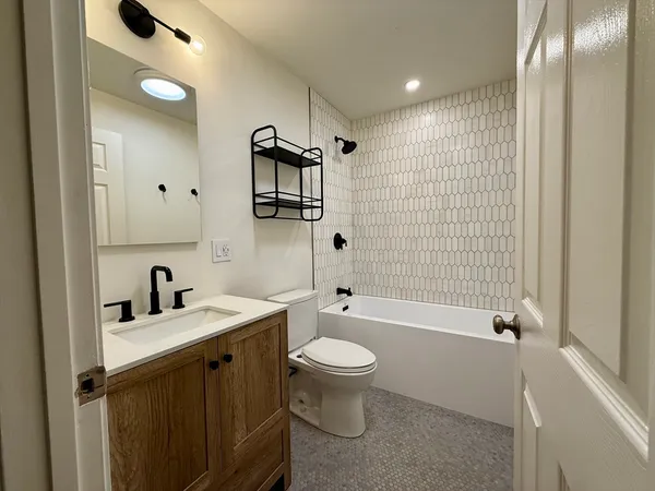 a bathroom with a bathtub shower sink mirror and toilet