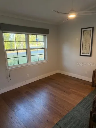 a view of an empty room with wooden floor and a window