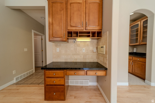 598 Hollow Creek Road Draper, UT 84020 - Photo 39 of 110 Built-in desk featuring a dark countertop, light wood cabinetry, and a neutral tile backsplash