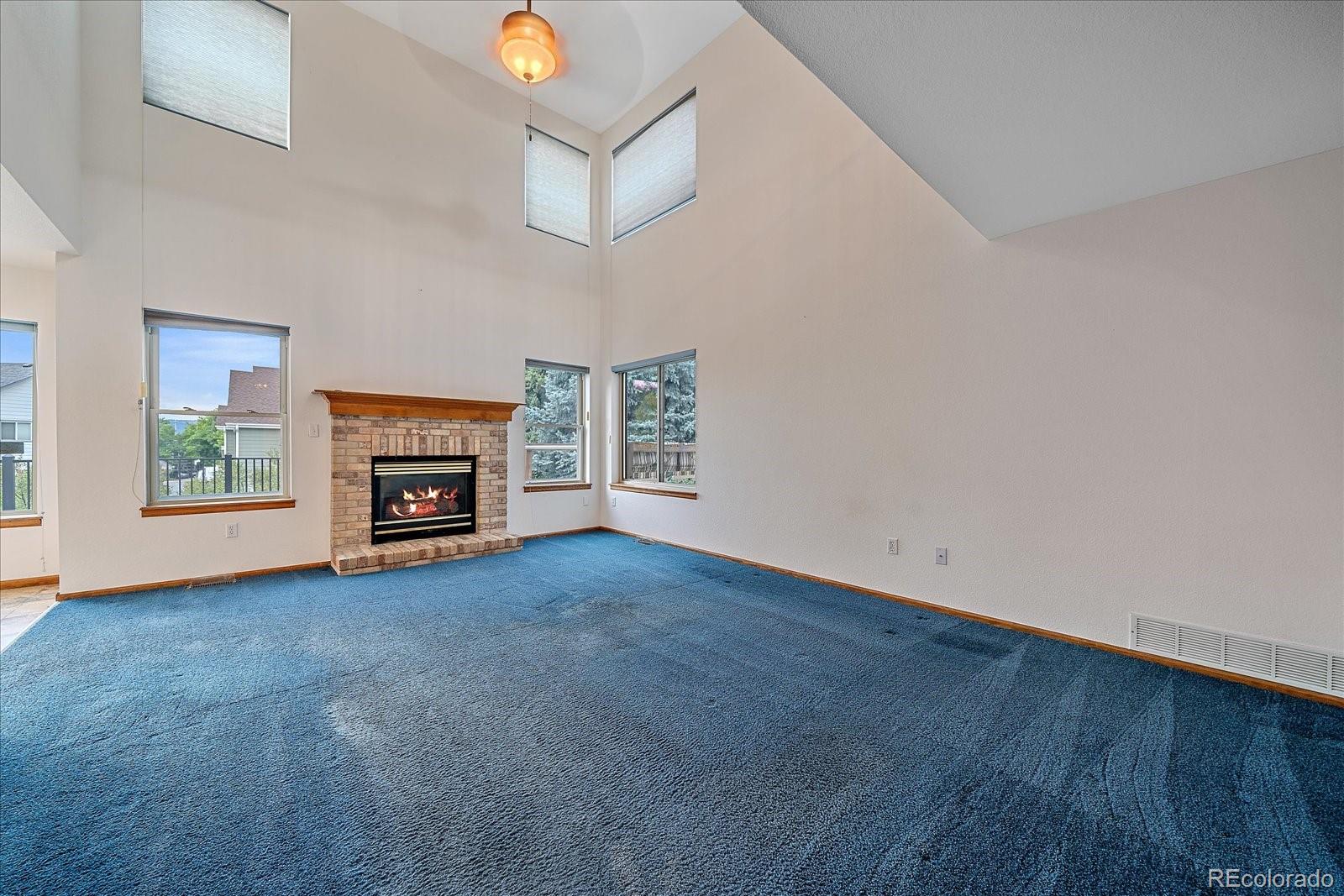 9875 Spring Hill Street Highlands Ranch, CO 80129 - Photo 8 of 38 an empty room with windows fireplace and a ceiling fan